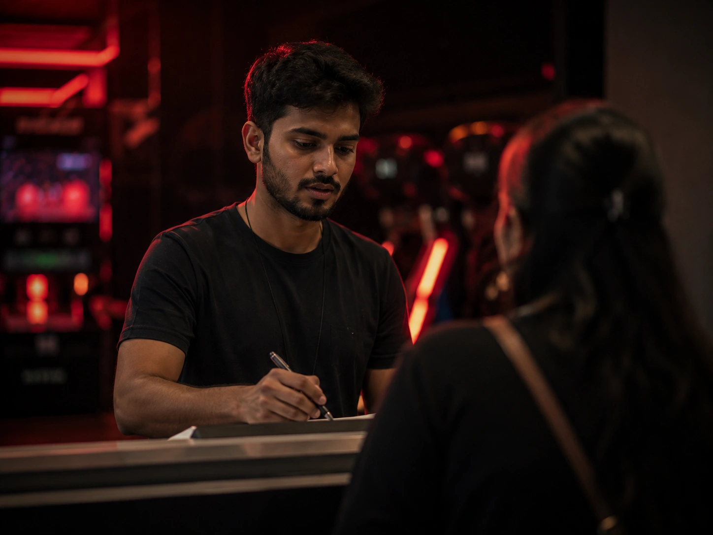 Activity centre host taking a group booking at a neon lit counter